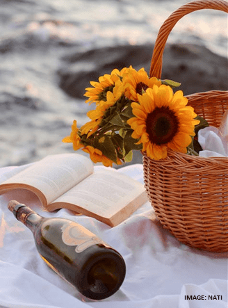 Photo of sunflowers in a basket with a book and a bottle of wine. For My Greek Books September 2023